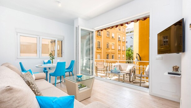 A modern living room with a sofa, chairs, a glass coffee table, and a TV mounted on the wall. - Solaga - Pinzon (Málaga)