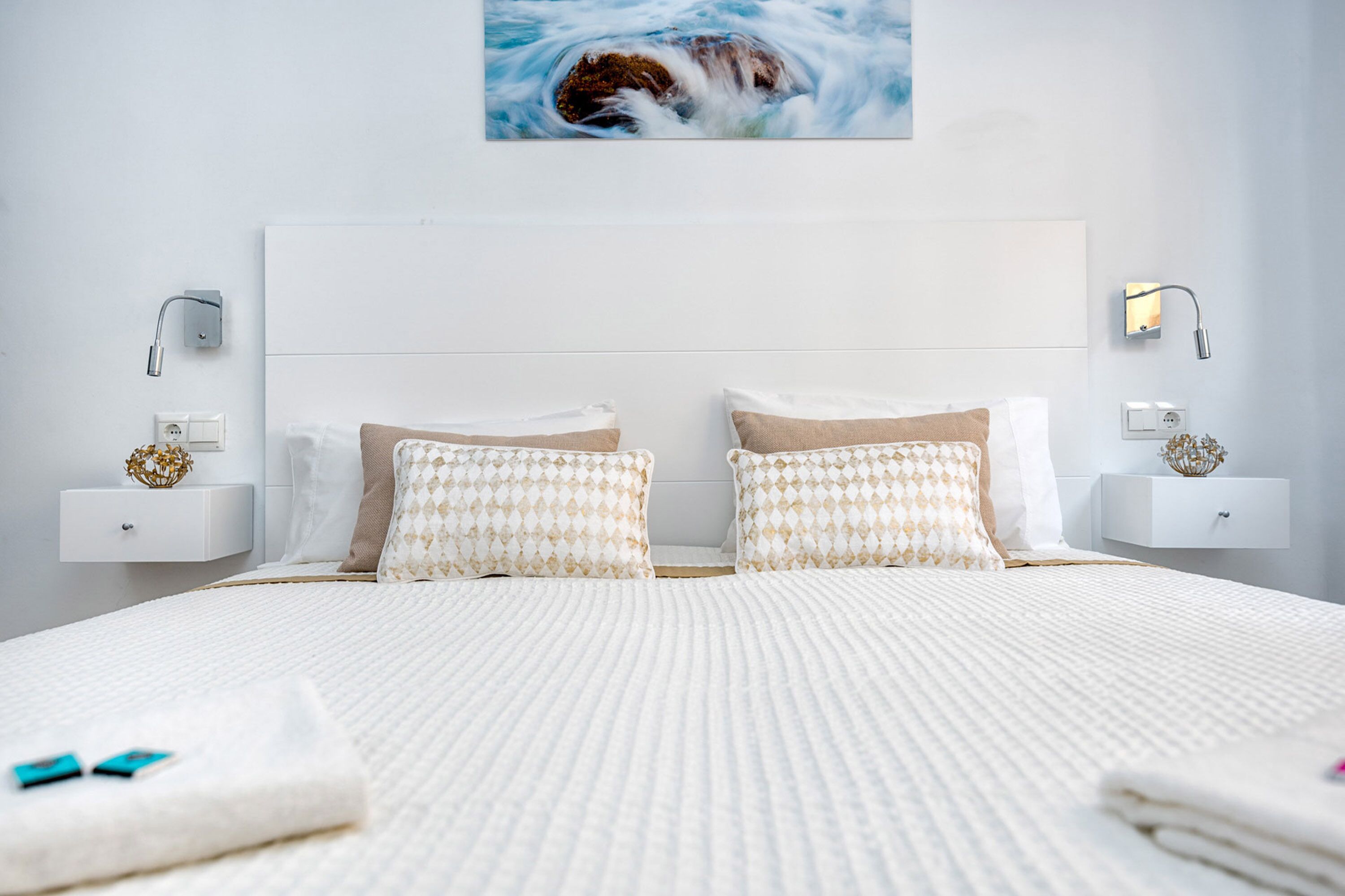 Une chambre moderne avec un grand lit, deux tables de chevet et un tableau accroché au-dessus du lit.