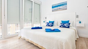 A bedroom with a large bed, a view of the outdoors through a sliding door, and a painting on the wall. - Solaga - Pinzon (Málaga)