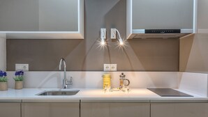A modern kitchen with a stainless steel sink, two pendant lights, a coffee maker, and a small potted plant. - Solaga - Pinzon (Málaga)