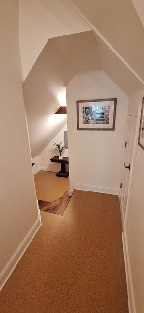 A narrow hallway with a sloped ceiling and a framed picture on the wall. - The Oak Park Loft (Oak Park)