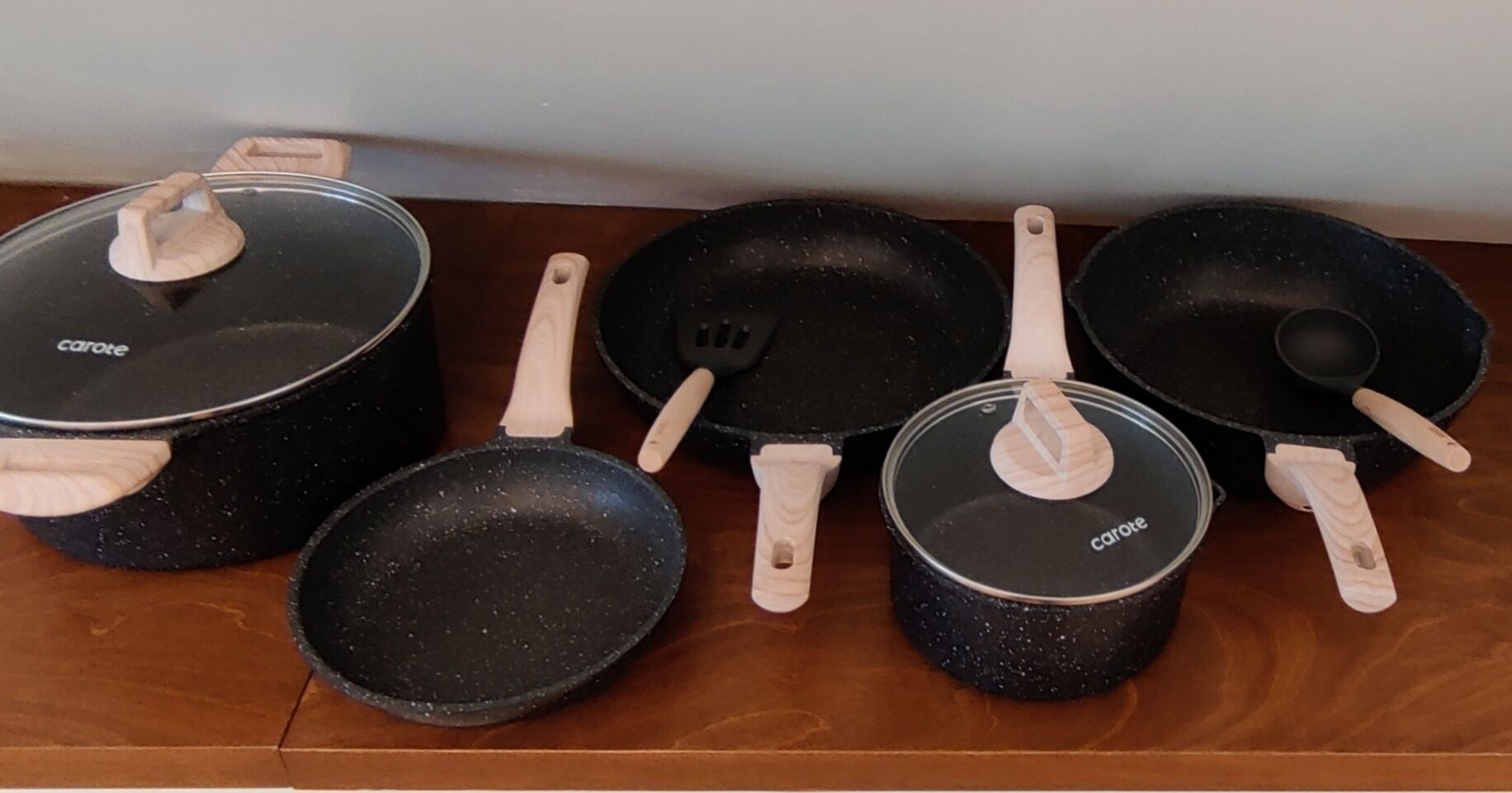 Una colección de utensilios de cocina, incluyendo ollas, sartenes y espátulas, sobre una superficie de madera.