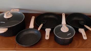 Una colección de utensilios de cocina, incluyendo ollas, sartenes y espátulas, sobre una superficie de madera.