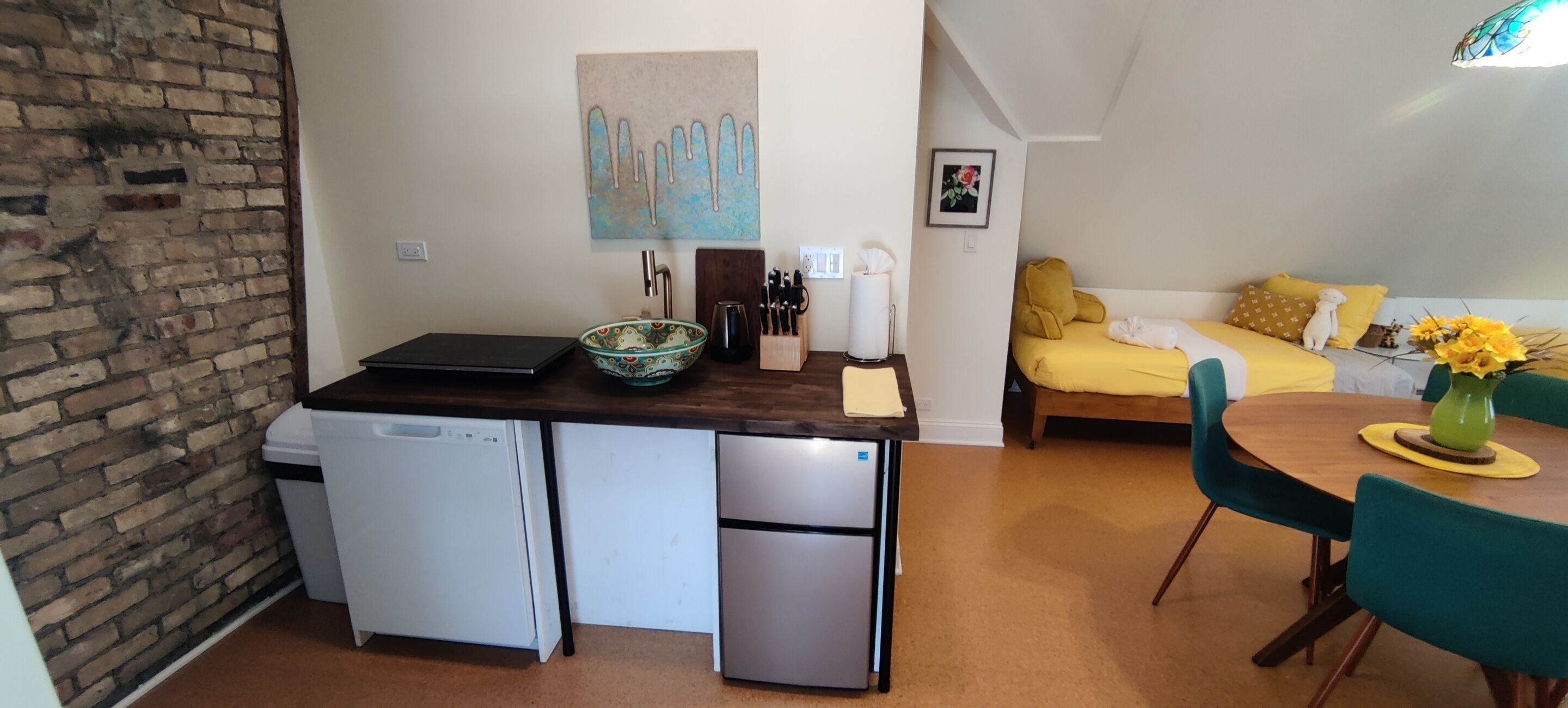 Una cocina compacta con lavavajillas, refrigerador y una pequeña zona de comedor con mesa y sillas.