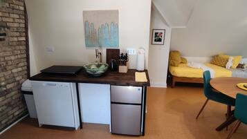 Una cocina compacta con lavavajillas, refrigerador y una pequeña zona de comedor con mesa y sillas.