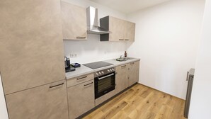 A kitchen with beige cabinets, a stainless steel range hood, a built-in oven, and a wooden floor. - Modern Apartment Milo 3 room apartment for up to 6 people (Küssaberg)