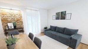 A modern living room with a grey sofa, a wooden dining table with chairs, a potted plant, and framed pictures on the wall. - Modern Apartment Milo 3 room apartment for up to 6 people (Küssaberg)