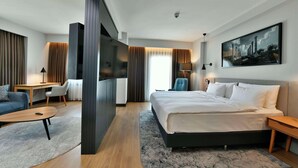 Ett modernt hotellrum med en stor säng, ett skrivbord, en stol och en TV.