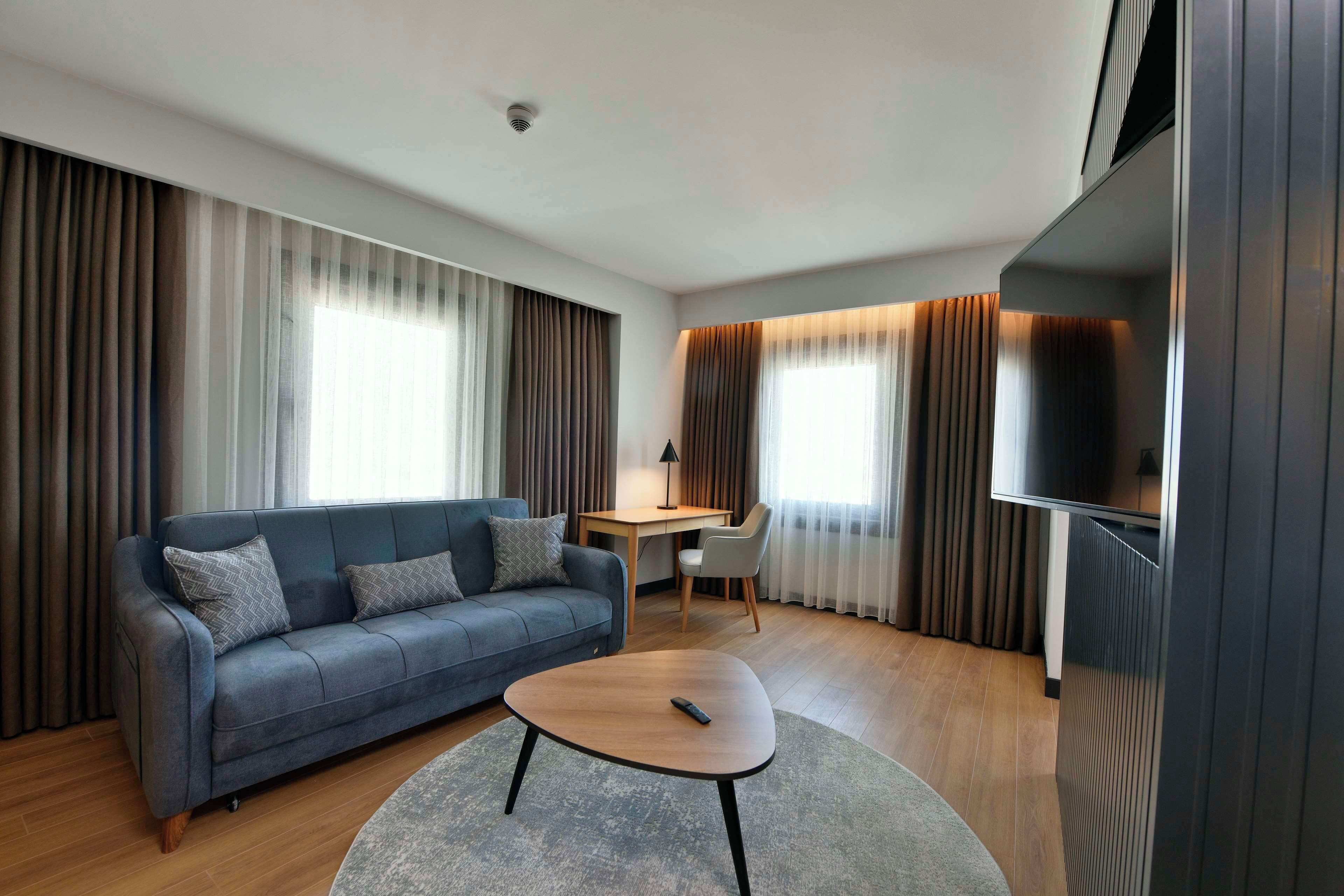 Una sala de estar moderna con un sofá, una mesa de centro, un escritorio y un televisor.