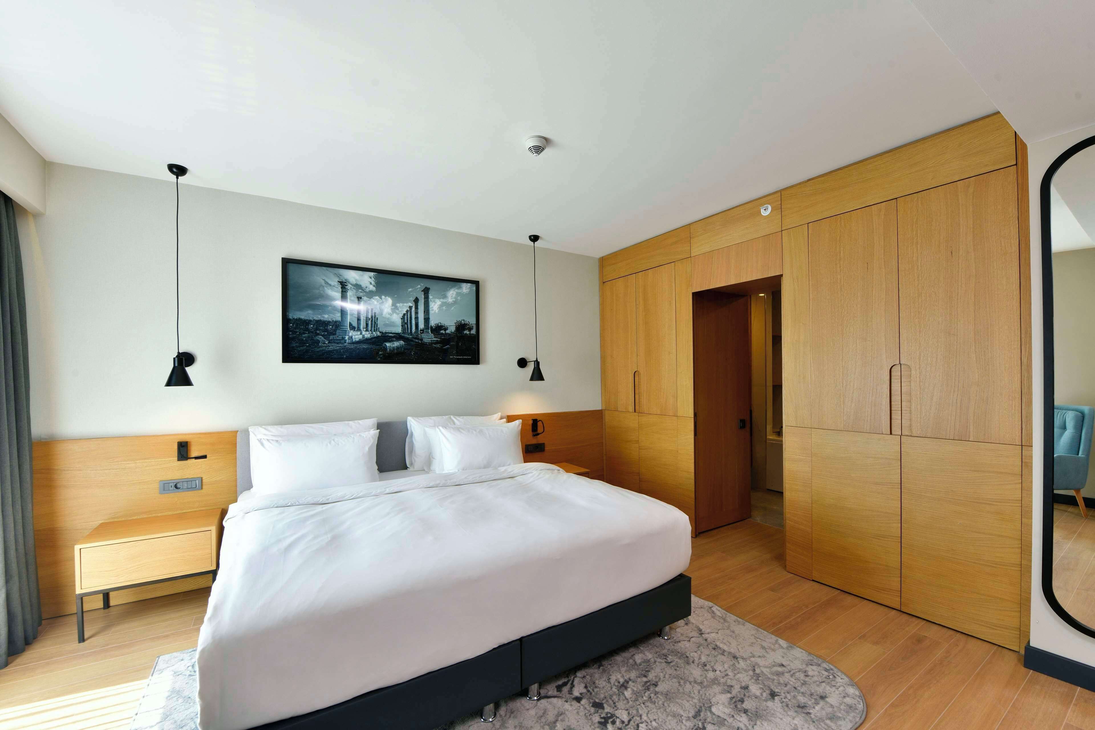 Un dormitorio moderno con una cama grande, un armario de madera y un cuadro de un paisaje urbano en la pared.