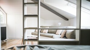 A loft-style bedroom with a sloped ceiling, a sofa, a small table, and a lamp. - Lake view attic  (Dagnente)
