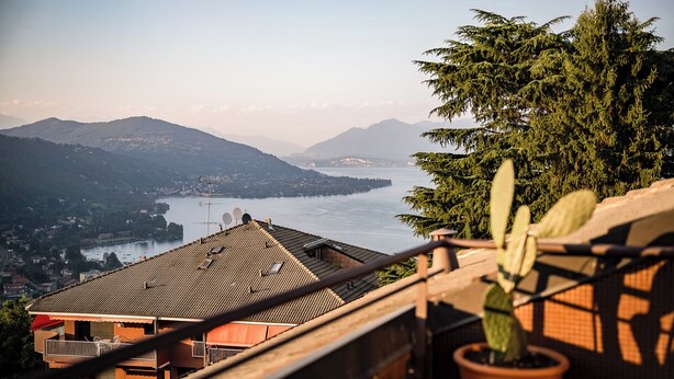 A terrace with a potted plant, overlooking a lake with mountains in the background. - Lake view attic  (Dagnente)