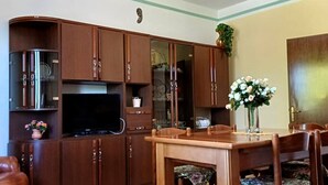 Un coin repas avec une table et des chaises en bois, un téléviseur et un ventilateur de plafond.