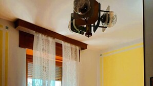 Une pièce comprenant un canapé, un projecteur fixé au plafond, des rideaux à motifs et un radiateur.