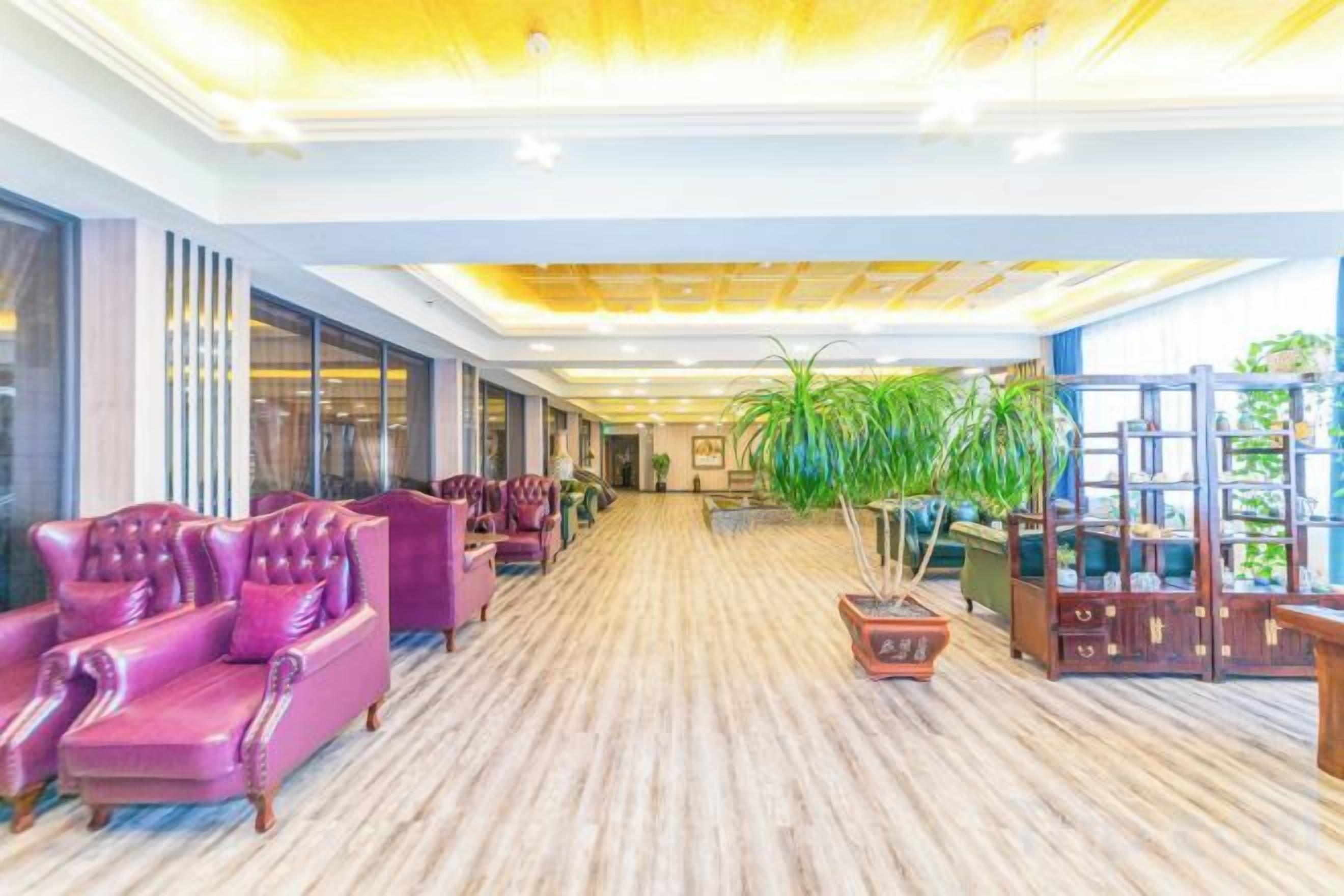 A hotel lobby with a wooden floor, purple seating, and a large plant.