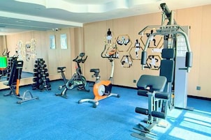 Un gimnasio con diversos equipos de ejercicio, incluyendo bicicletas estáticas, cintas de correr y máquinas de pesas.