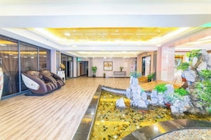 A spa area with a massage chair, a reception desk, and a water feature. - Friendship Peak Hotel (Burqin)