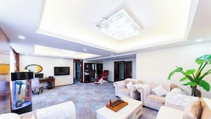 A spacious living room with a high ceiling, a chandelier, a large plant, and a television. - Friendship Peak Hotel (Burqin)