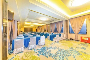 A conference room with rows of tables, chairs, and a carpeted floor. - Friendship Peak Hotel (Burqin)