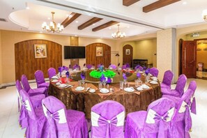 A conference room with a round table, purple chairs, and a chandelier. - Friendship Peak Hotel (Burqin)