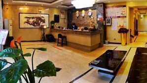 A hotel lobby with a reception desk, a large painting, a clock, and a coffee table.