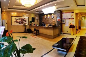 A hotel lobby with a reception desk, seating area, and a large plant. - Century Business Hotel (Meitan)