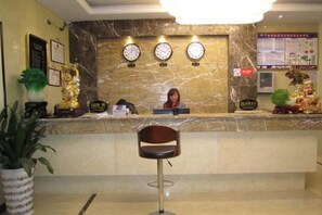 A reception area with a marble counter, a receptionist, a clock, and a potted plant. - Century Business Hotel (Meitan)