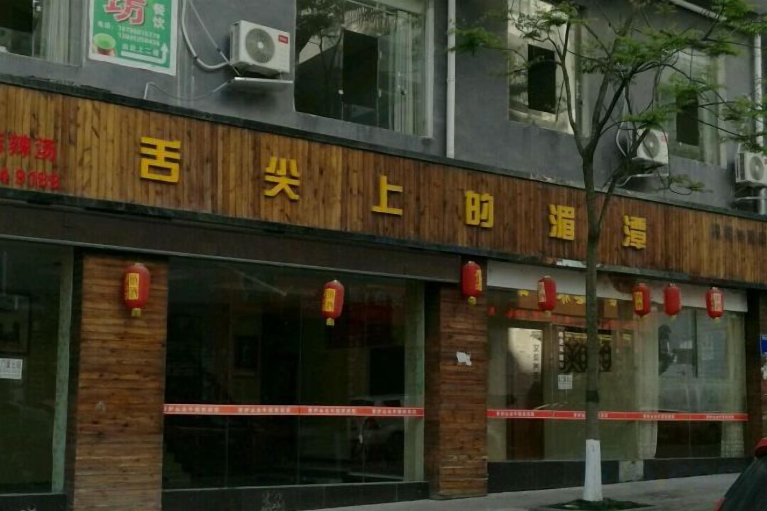 A building with a sign that reads '吉尖上帮' and a storefront with large windows and red lanterns.