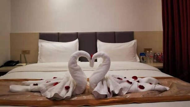 A hotel room with a bed, a nightstand, and a bedside table.