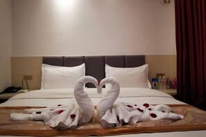 A hotel room with a bed, a nightstand, and a bedside table. - Century Business Hotel (Meitan)