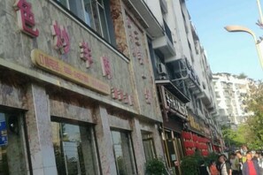 A building with multiple storefronts, including one with a sign that reads 'colorful animal skin.' - Century Business Hotel (Meitan)
