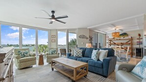 A spacious living room with a large window, a ceiling fan, and a view of the ocean. - Seaspray Riverside 313 (Pensacola)