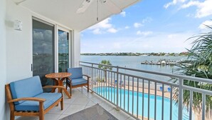 A balcony with a pool, wooden furniture, and a view of the water and dock. - Seaspray Riverside 313 (Pensacola)