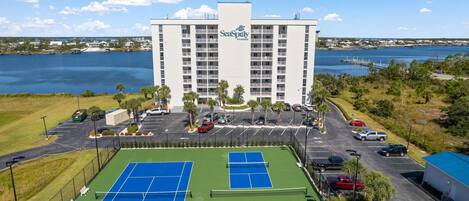 A hotel with a tennis court and a parking lot.