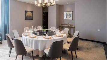 A round dining table with chairs, a chandelier, and a fireplace in the background.