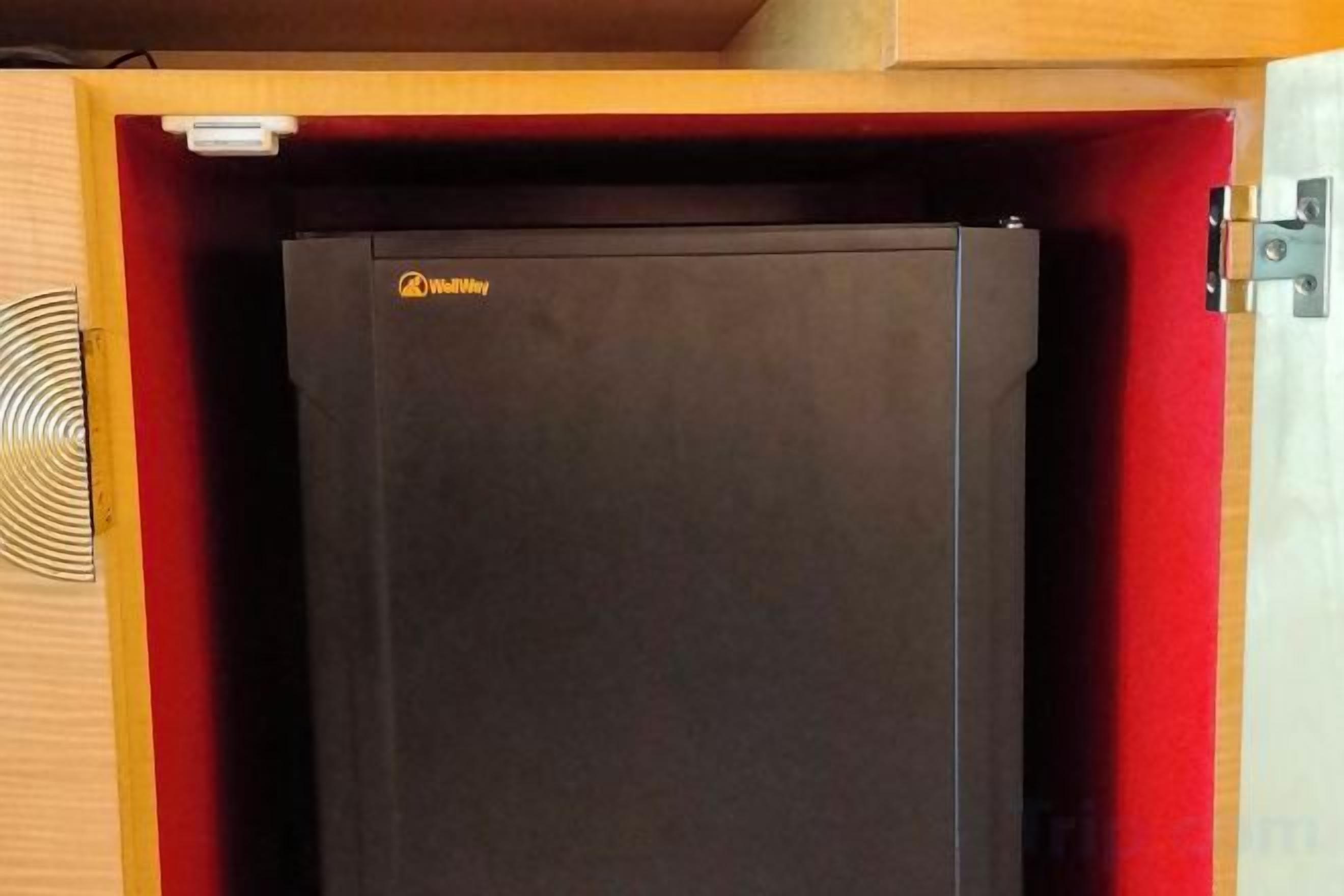 A black refrigerator in a wooden cabinet with a red interior.