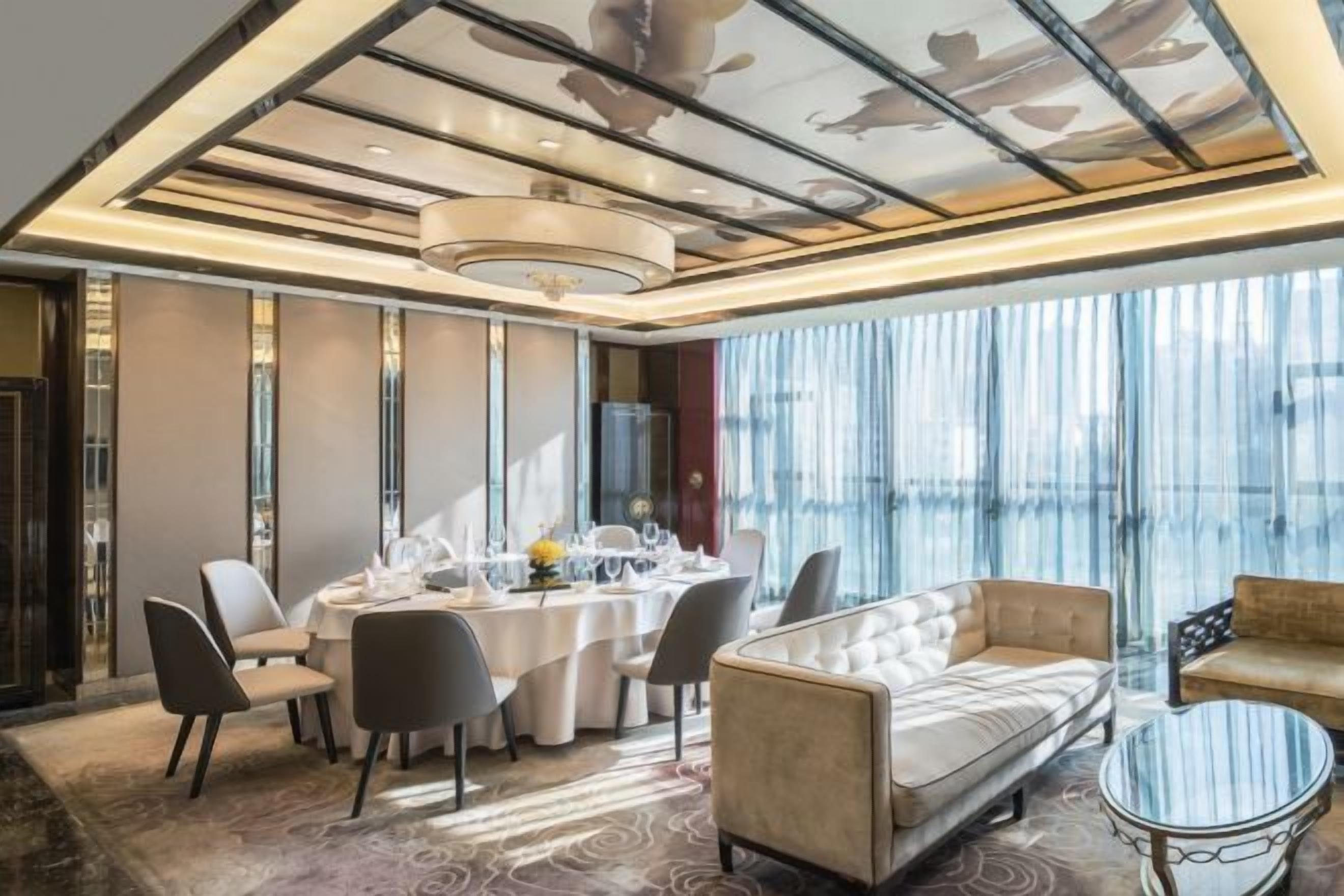 A modern dining area with a round table, chairs, and a sofa.