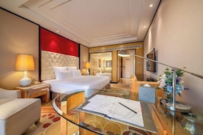 A hotel room with a bed, a desk, a chair, a lamp, a vase with flowers, and a mirror. - Landmark Hotel (Guangxi University) (Nanning)