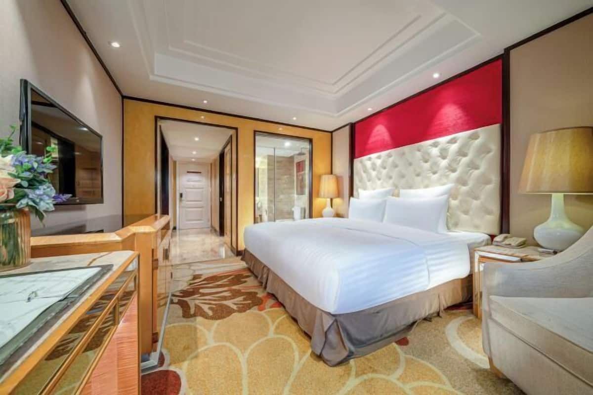 Una habitación de hotel con una cama grande, televisión, escritorio y una silla.