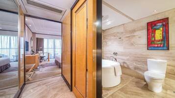 Une chambre d’hôtel avec une porte en bois, une salle de bain avec une baignoire et des toilettes, et une vue sur l’intérieur de la chambre.
