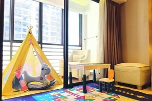 A room with a play tent, a rocking horse, a small table, a chair, and a colorful play mat.