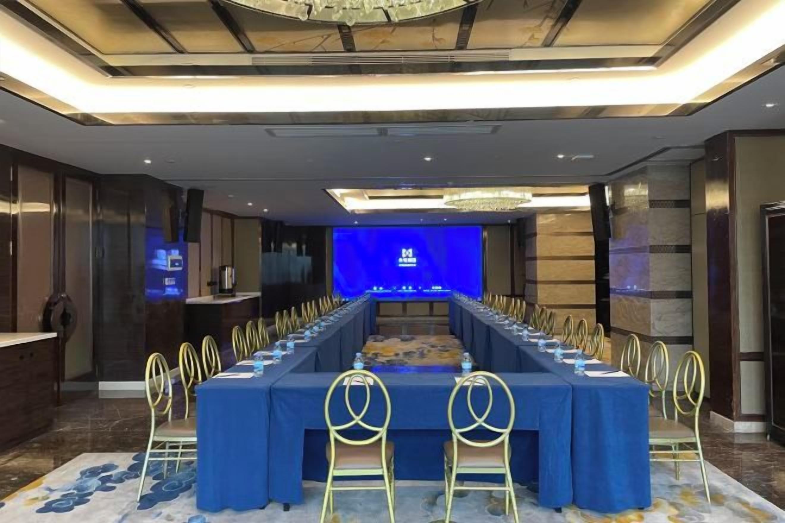 A conference room with a long table, chairs, and a screen at the front.
