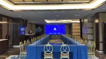 A conference room with a long table, chairs, and a screen at the front.