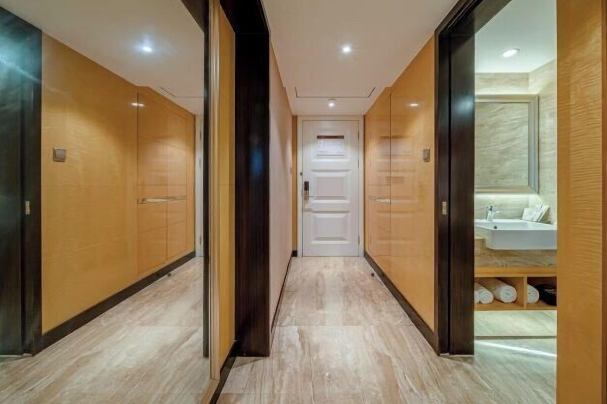 Un pasillo con puertas de madera y un baño a la derecha.