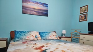 A bedroom with a bed, a nightstand, a dresser, a lamp, and a television. - Southern Comfort Sicily Holidays (Letojanni)