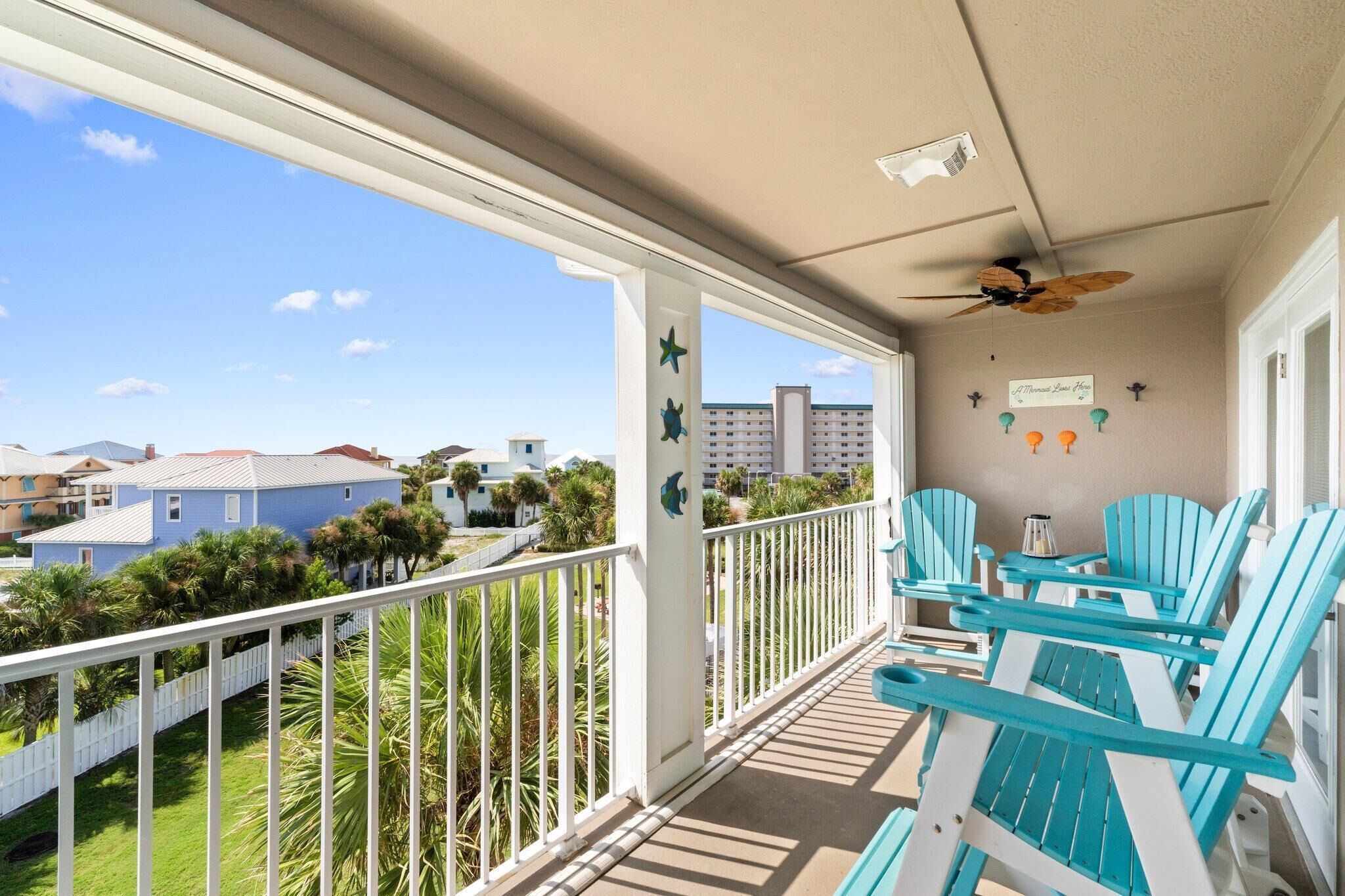 Een balkon met uitzicht op een woonwijk, een plafondventilator en een bordje met de tekst 'Aloha Room'.