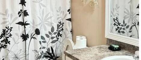 A bathroom with a toilet, sink, and shower curtain with a floral pattern.