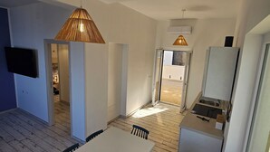 Een moderne keuken met een inbouwkoelkast en een eethoek met een witte tafel en donkere stoelen.