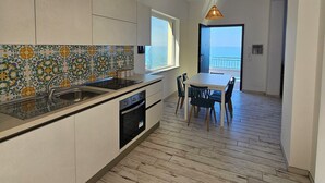 Een moderne keuken met een groot eiland, een eetgedeelte met uitzicht en een houten vloer.
