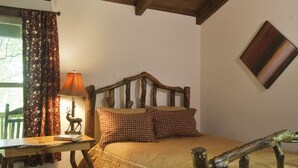 A rustic bedroom with a wooden headboard, a desk with a lamp, and a deer figurine.